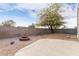 Well-maintained backyard featuring a fire pit, large tree, rock landscaping, and privacy fence at 14838 N 172Nd Ln, Surprise, AZ 85388