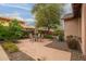 Outdoor dining area on a paver patio with mature landscaping and a covered patio area at 15289 W Valentine St, Surprise, AZ 85379