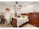 Cozy bedroom features a ceiling fan, complementary wall art, and beautiful wood furnishings at 15289 W Valentine St, Surprise, AZ 85379