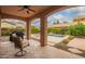 Picturesque covered patio with comfortable seating and outdoor grill overlooking the luxurious pool area at 15289 W Valentine St, Surprise, AZ 85379