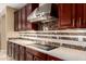 Close-up of a modern cooktop with stainless steel range hood and marble backsplash at 15289 W Valentine St, Surprise, AZ 85379