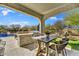 A luxurious outdoor kitchen and dining area next to the pool, designed for ultimate outdoor entertaining and relaxation at 16987 W Princeton Ave, Goodyear, AZ 85395