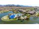 Community aerial view showcasing a clubhouse, pool, lush landscaping, lake, and desert mountain backdrop at 18182 W Glenhaven Dr, Goodyear, AZ 85338