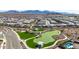 Aerial view of a community park with green space, walking paths, and mountain views in the distance at 18182 W Glenhaven Dr, Goodyear, AZ 85338