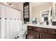 Stylish bathroom features a shower with a white curtain, dark wood vanity, and decorative accents at 18182 W Glenhaven Dr, Goodyear, AZ 85338