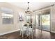 Cozy dining area with a chandelier, wood floors, and sliding glass door leading to the outdoor space at 18182 W Glenhaven Dr, Goodyear, AZ 85338