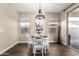 Bright dining area with a modern chandelier, wood floors, and a sliding glass door to the patio, perfect for entertaining at 18182 W Glenhaven Dr, Goodyear, AZ 85338