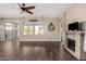 Bright and airy living room with a stone fireplace, wood-look flooring, and access to the outdoor patio at 18182 W Glenhaven Dr, Goodyear, AZ 85338