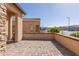 A spacious outdoor patio featuring neutral-colored pavers with low brick wall and relaxing scenic view at 18182 W Glenhaven Dr, Goodyear, AZ 85338