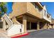 View of tan stucco building with covered parking, stairs, and drought-resistant landscaping under a sunny blue sky at 2035 S Elm St # 218, Tempe, AZ 85282