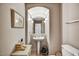 Well-lit powder bathroom with a pedestal sink, arched mirror, and neutral walls at 26560 N 115Th St, Scottsdale, AZ 85255