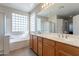 Bathroom featuring a dual vanity, soaking tub, and a glass block window providing natural light at 3524 E Derringer Way, Gilbert, AZ 85297