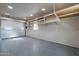 This is an empty garage with gray floor, shelves, and a silver garage door at 3524 E Derringer Way, Gilbert, AZ 85297