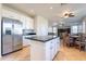 Bright kitchen with an island, stainless steel refrigerator and view into dining and living area at 3524 E Derringer Way, Gilbert, AZ 85297