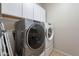 Laundry room features a gray front-load washing machine, white dryer, and white cabinets for storage at 3524 E Derringer Way, Gilbert, AZ 85297