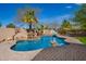 Backyard pool with rock waterfall feature, basketball hoop, and lush landscaping for outdoor enjoyment at 3562 E Harvard Ct, Gilbert, AZ 85234