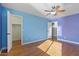 Spacious bedroom features wood floors, a ceiling fan, and light blue and purple accent walls at 366 E Mule Train Trl, San Tan Valley, AZ 85143