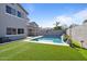 Refreshing backyard swimming pool, lush artificial turf, and privacy wall in the background at 366 E Mule Train Trl, San Tan Valley, AZ 85143