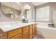 Bathroom featuring double sinks, soaking tub, glass block window, and tiled floor at 44 W Teakwood Pl, Chandler, AZ 85248