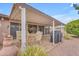 Covered patio with outdoor seating showcases the backyard's xeriscaping and mature trees at 4720 E Flossmoor Cir, Mesa, AZ 85206