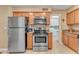 Well-lit kitchen featuring stainless steel appliances, wood cabinets, and easy access to the laundry room at 4720 E Flossmoor Cir, Mesa, AZ 85206