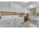 Bright laundry room features white cabinetry, washer, dryer, desk area, and a window providing natural light at 4720 E Flossmoor Cir, Mesa, AZ 85206