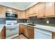 Bright kitchen featuring light wood cabinets, white appliances, black backsplash, and white countertops at 4950 N Miller Rd # 231, Scottsdale, AZ 85251