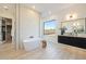 Bright bathroom featuring a soaking tub, stylish vanity, a stone accent wall, and a large window at 510 E Woburn Ln, Phoenix, AZ 85085