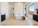 Modern bathroom with a freestanding tub, wood-look tile flooring, stone accent wall, and bright lighting at 510 E Woburn Ln, Phoenix, AZ 85085