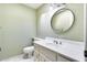 Well lit powder room with a round mirror above the vanity and light green colored walls at 5501 E Camelback Rd, Phoenix, AZ 85018