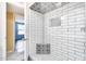 Updated shower showcasing stylish tiling, a built-in corner seat and a convenient toiletry niche at 5501 E Camelback Rd, Phoenix, AZ 85018