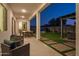 Inviting covered patio with outdoor dining and cozy seating, overlooking the landscaped backyard at twilight at 5508 N 192Nd Ave, Litchfield Park, AZ 85340