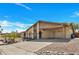 A charming single-story home boasts a covered carport, desert landscaping, and a long, paved driveway under a clear sky at 635 W Pecos Ave, Mesa, AZ 85210