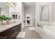 Bright bathroom featuring marble counters, dual sinks, soaking tub, glass enclosed shower, and neutral color scheme at 7525 E Gainey Ranch Rd # 110, Scottsdale, AZ 85258