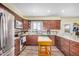 Bright kitchen features dark wood cabinets, tile backsplash, stainless steel appliances and center island at 8431 W Planada Ln, Peoria, AZ 85383