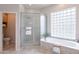 Well-lit main bathroom featuring a glass enclosed shower and a large soaking tub with tile surround at 9113 N 116Th Way, Scottsdale, AZ 85259