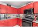 This beautiful kitchen features striking red cabinets, granite countertops, and stainless steel appliances at 11234 W Roma Ave, Phoenix, AZ 85037