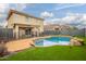 Backyard showcasing a sparkling pool with rock features, artificial turf, and a covered patio at 11234 W Roma Ave, Phoenix, AZ 85037