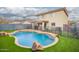 Home with a sparkling backyard pool, mature palm tree, and artificial turf at 11234 W Roma Ave, Phoenix, AZ 85037