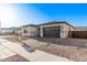 Charming single-story home with desert landscaping, a paved driveway, and a two-car garage at 15846 W Bronco Trl, Surprise, AZ 85387
