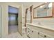 A well-lit bathroom featuring a large mirror, single vanity, tiled floor, and a door to a shower room at 17244 N 66Th Ln, Glendale, AZ 85308