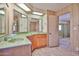 Bathroom featuring a vanity with green countertop, lots of mirrors, a light wood trim and a view of the bedroom at 17244 N 66Th Ln, Glendale, AZ 85308
