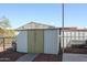 This home boasts an outdoor storage shed with dual-doors, surrounded by gravel, with blue skies overhead at 17244 N 66Th Ln, Glendale, AZ 85308