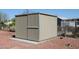 Close view of a large backyard shed with modern sliding doors, concrete base and gravel ground at 17244 N 66Th Ln, Glendale, AZ 85308