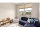 Bright playroom with large windows, blue sofa, playroom rug, and lots of toys at 17845 W Red Fox Rd, Surprise, AZ 85387