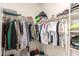 Well-organized walk-in closet with hanging clothes and shelving at 17845 W Red Fox Rd, Surprise, AZ 85387