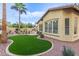 The lush backyard boasts an artificial lawn, mature landscaping, and a charming facade of the home at 21008 W Cora Vis, Buckeye, AZ 85396