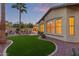 The lush backyard boasts an artificial lawn, mature landscaping, and a charming facade of the home during sunset at 21008 W Cora Vis, Buckeye, AZ 85396