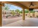 Relaxing covered patio with an outdoor fireplace, ceiling fan, and lush landscaping at 21008 W Cora Vis, Buckeye, AZ 85396