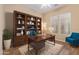 Well-appointed home office with custom shelving, a large desk, and comfortable seating for productivity at 21008 W Cora Vis, Buckeye, AZ 85396